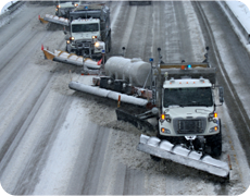 Snowplow trucks remove snow from a highway